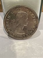 Obverse side of 1958 Canadian silver dollar coin showing Queen Elizabeth II profile and inscriptions.