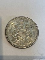 Obverse side of the silver 1961 Canadian 50 cent coin showing the Canadian coat of arms with the year 1961 and denomination.