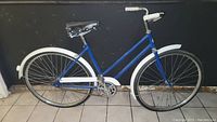 Full side view of the vintage blue bicycle showing frame, wheels, saddle, handlebars, and fenders.