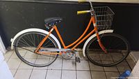 Orange 1950s vintage CCM bicycle showing the right side full view with chain guard, rear wheel, saddle, and frame.