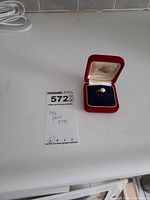 Ring in open red velvet case with auction lot card visible