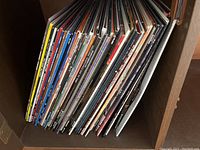 Shelf view showing a stack of approximately 30 vinyl LP record sleeves stored upright