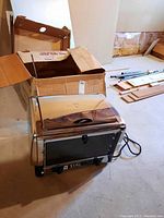 Photo showing the stainless steel Black Angus oven with cardboard box and accessories.