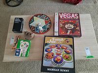 Overview photo of all games and items on table showing the Vegas game box, Family Fun Michigan Rummy box, Cards Against Humanity box, View Master, Stanline playing cards, and dragon domino board.