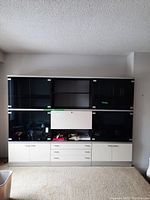 Front view of the 3 section wall unit showing 3 drawers in the center, 8 glass doors on the upper sections, and 5 wood doors on the lower sections.