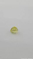 Natural pear cut lemon yellow citrine gemstone shown against a plain background, highlighting its color and cut.