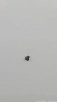 Close-up image of a small heart-shaped sapphire gemstone on a plain white background showing its color and cut details.