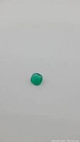 5.46 carat vivid lime green onyx gemstone against plain background showing color and size.