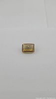 Front view of the rectangular golden citrine gemstone showing its checkerboard cushion cut and deep yellow color.