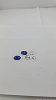Five loose gemstones displayed on white background: 2 blue Lapis Lazuli and 3 clear crystal quartz.