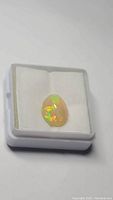 Opal gemstone in a display box showing play-of-color
