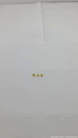 Three small round loose yellow-green sphene gemstones on white background, arranged in a row.