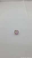 Photo of a cushion cut Ametrine gemstone with bright purple and golden hues on white background, centered view.