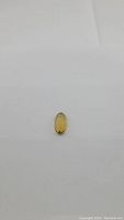 Single natural champagne-colored citrine gemstone, long oval cut, photographed against a neutral background to show clarity and color.