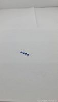 Four small oval cut gemstones laid out horizontally showing cornflower blue color, on plain white background.