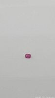 Natural deep pink red emerald cut ruby gemstone on white background, small size