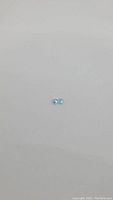 Pair of small round sky blue topaz gemstones placed on a plain surface, showing the size and color.