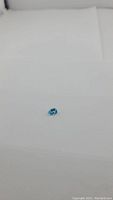 Pear-shaped natural Swiss blue topaz gemstone on white background, showing blue color and cut.