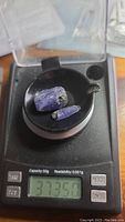 Two natural tanzanite crystals on a digital scale weighing 37.35 carats total, one large and one smaller piece.