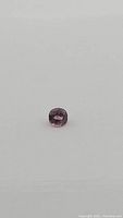 Close-up front view of natural lavender pink spinel gemstone on a white background