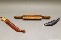 Closed red sheath, etched wooden base, black sheath and blade arranged on grey surface