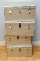 Four silver aluminum cases stacked vertically showing front latch closures.