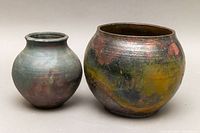Two signed pottery pots placed side by side showing size difference and multicolored glaze details.
