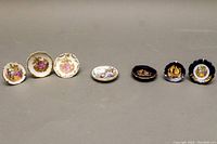 Full view of the seven Limoges hand painted miniature decorative plates arranged in a row