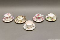 Five different teacup and saucer sets with floral and gold rim designs shown from above and angled views.