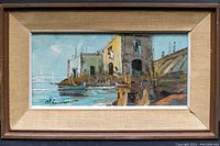 Framed signed oil on canvas painting showing waterfront buildings by dock with maritime theme, signature visible in lower left corner.