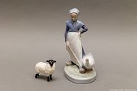 Front and side view of the Goose Girl figurine with a Beswick porcelain sheep figurine beside it on a neutral surface.