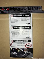 Black plastic Myers Orléans Nissan license plate frame paired with promotional cards showing service options and prices