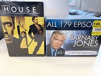 Full view of the two DVD boxed sets side-by-side: House M.D. and Barnaby Jones complete series, both unopened.