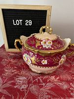 Full view of the vintage Limoges tureen with lid on, showing pink and gold colors with floral motifs and gold handles