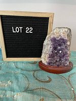 Purple amethyst crystal in a natural rough form with crystal points visible, attached to a round reddish-brown wooden stand.