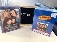 Box set of Sisterhood of the Traveling Pants DVD and Seinfeld Complete Series DVD, with lot number board behind.