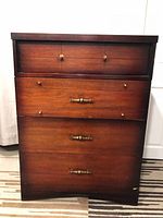 Front view of vintage highboy dresser showing wood finish, original hardware, and wear marks.