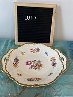 Oval fine china bowl with floral print and gold scalloped edges shown from a top angle with 'LOT 7' sign