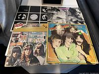 Photo showing five vinyl albums on a table with various band covers including Trooper, The Spoons, and Sweet, all used and untested.
