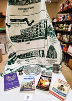 Photo showing a green and white Phoenixville Hospital commemorative throw surrounded by two pewter plates, a pewter mug, four books, and a ceramic Liberty Bell.