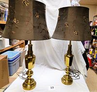 Pair of brass table lamps side by side showing glossy brass bases and embroidered dark fabric shades