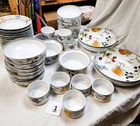 Full spread of stack of dinner plates, bowls, ramekins and serving bowls showing fruit pattern