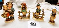 Four Hummel figurines together showing characters: boy and girl duo, girl on fence with bird, boy on fence with bird, and girl holding basket.