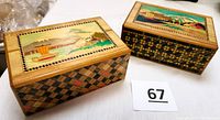 Photo showing two Japanese wooden puzzle boxes with scenic artwork on top and Ichimatsu checkered inlay on sides.