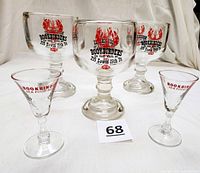 Full view of three large pedestal beer glasses and two smaller mini martini glasses, all branded with Old Original Bookbinders seafood restaurant logos and addresses