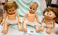 Photo of three vintage dolls seated, all wearing diaper-style underwear, showing their body features and hair styles