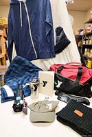 Lot laid out showing all items including hoodie, hat, caps, scarf, bag, umbrella, travel mug, blanket, journal