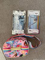 Top view showing two factory-sealed license plate holders, one US Air Force and one rainbow design, along with a Disney-themed lunchbox with rainbow strap.