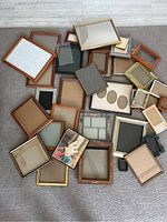 Overview of assorted picture frames spread on floor with varied sizes and styles.