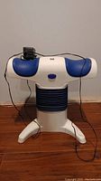 Front view of the Back2Life adjustable back machine showing blue padded arm supports and power cord.